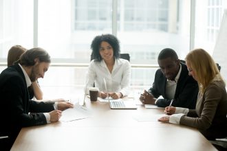 Businessman and businesswoman signing contracts at group multiracial meeting, two smiling male and female new partners making deal after successful negotiations putting signature on business papers